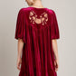 Elegant woman in red velvet mini dress with embroidered back and tassels, perfect for special occasions.