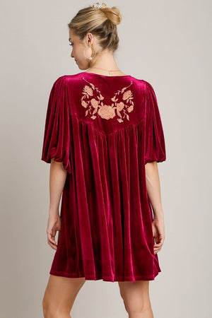 Elegant woman in red velvet mini dress with embroidered back and tassels, perfect for special occasions.