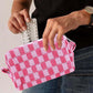 Woman holding a pink checkered knitted cosmetic pouch with zipper, showcasing its stylish and functional design.