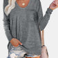 Woman wearing Bella Road gray round neck long sleeve T-shirt with pocket, paired with ripped denim shorts and carrying a beige handbag.