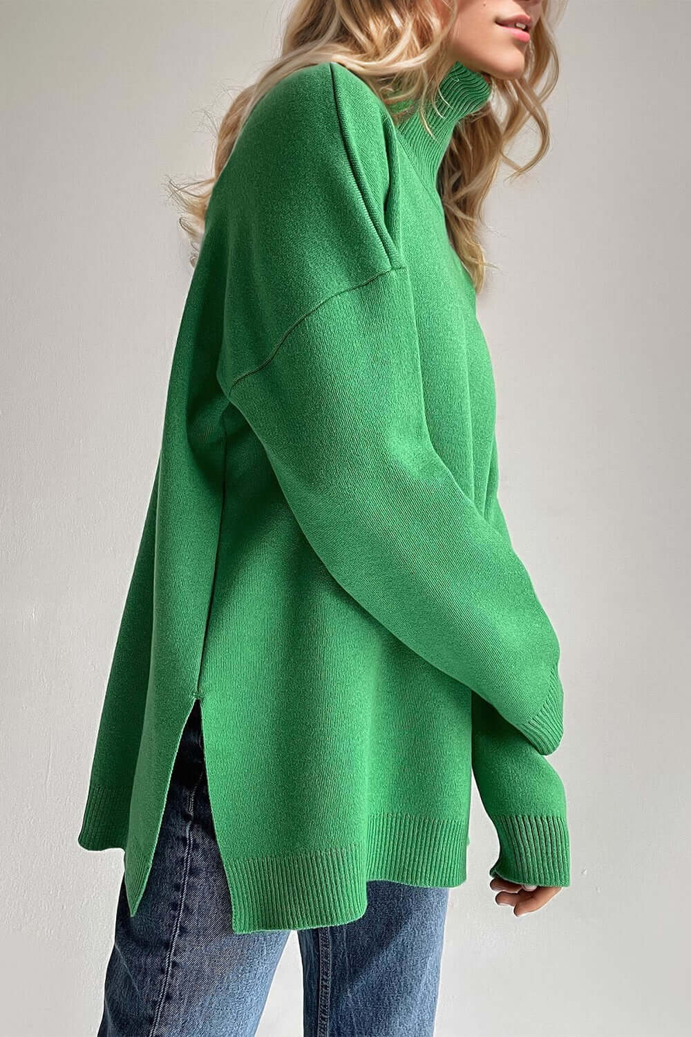 Woman wearing green turtleneck sweater with side slits and dropped shoulders, perfect blend of style and comfort for any season