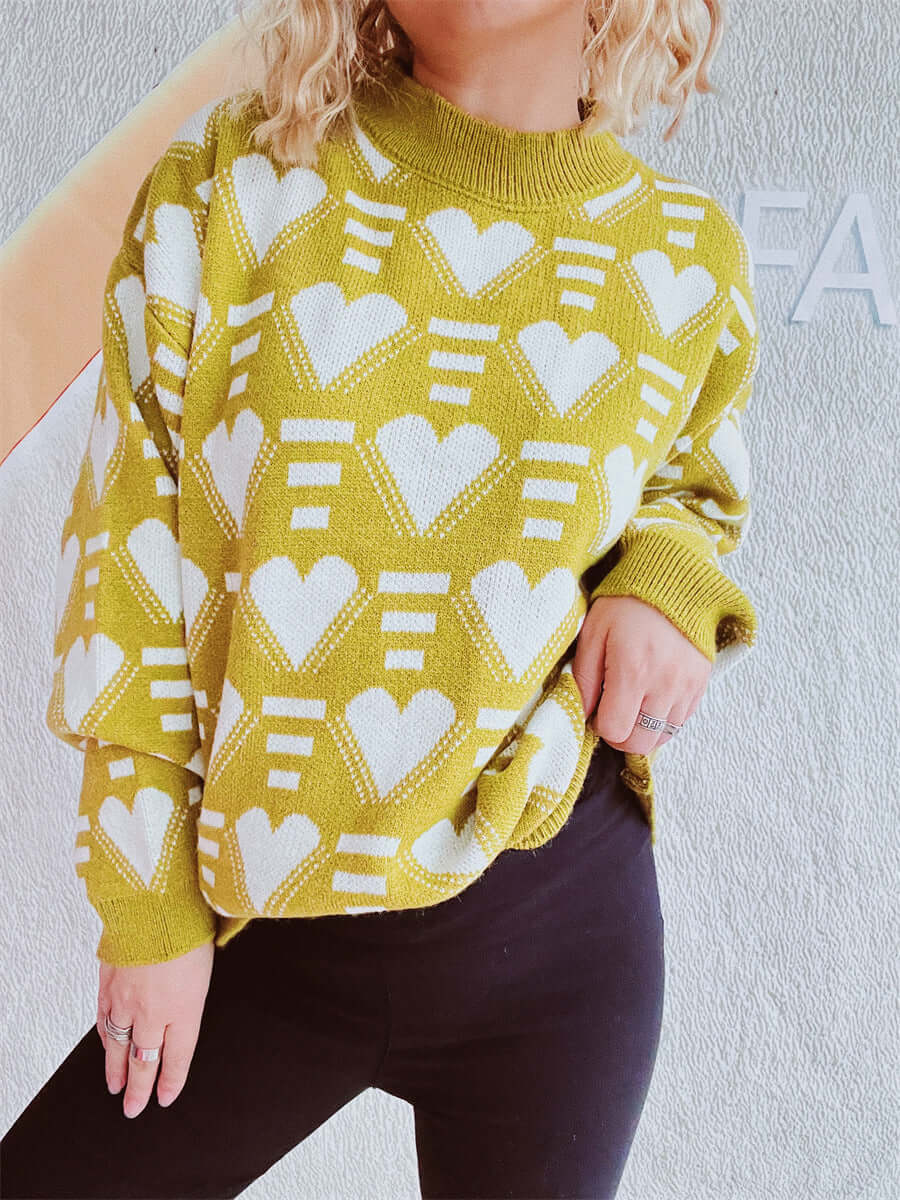 Woman wearing Bella Road Heart Contrast Long Sleeve Dropped Shoulder Sweater with playful white heart design against a vibrant yellow background.