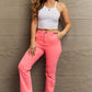 Woman wearing pink Kenya High Waist Side Twill Straight Jeans by Risen Jeans, paired with white top and shoes, posing confidently.