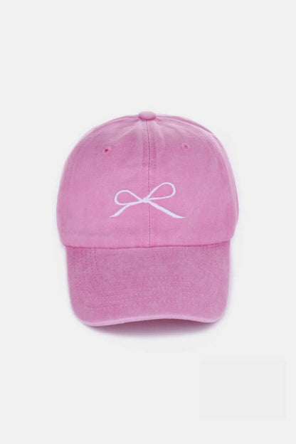 Pink bow embroidered washed cotton cap with delicate white bow design, stylish and comfortable headwear for a playful and elegant look.