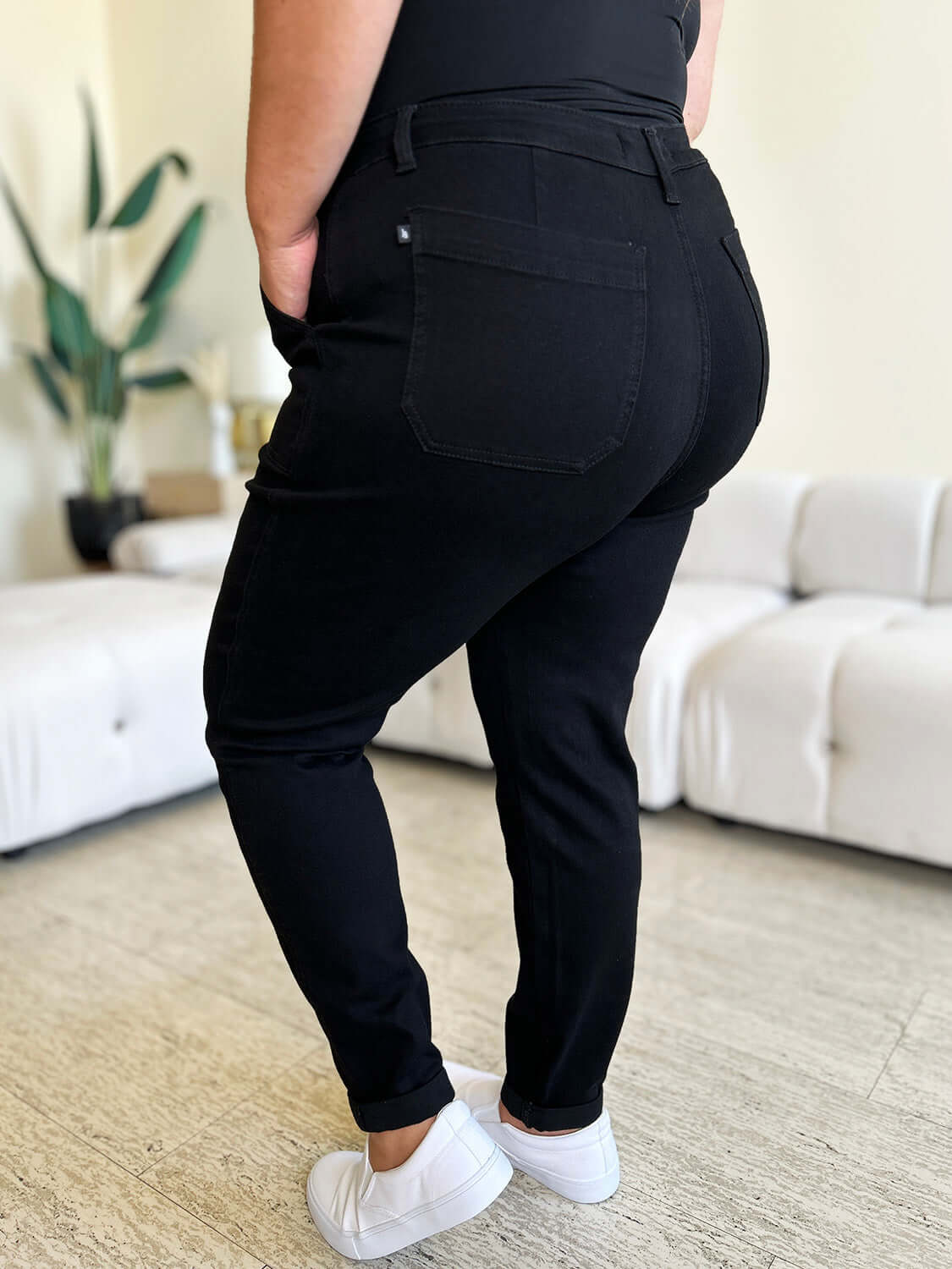 Back view of person wearing black High Waist Double Roll Cuff Jeans from Judy Blue Jeans, showcasing the flattering fit and stylish cuff detail.