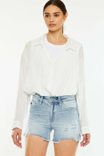 Woman wearing high rise side slit denim shorts and a white blouse