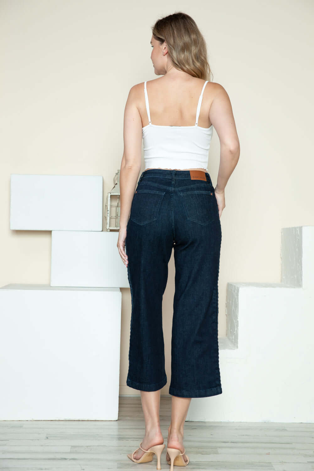 Woman wearing Judy Blue crop wide leg jeans with side seam braid detail from the back, styled with a white top.