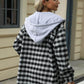 Woman wearing Bella Road Drawstring Plaid Long Sleeve Hooded Jacket in black and white, standing outdoors.