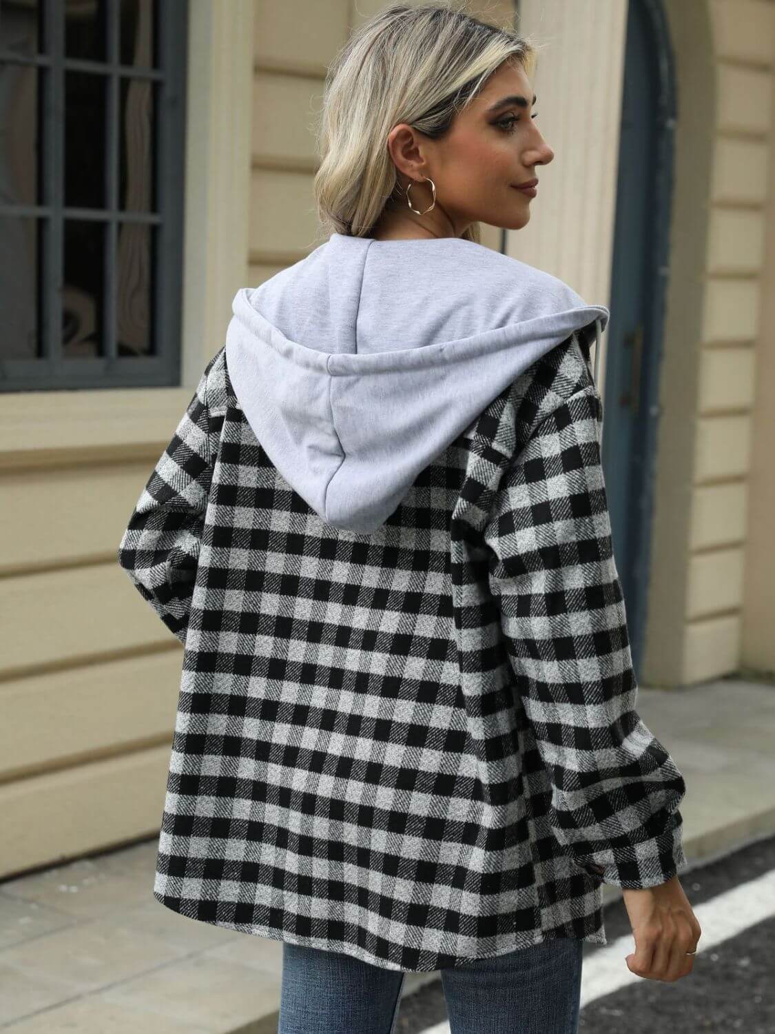 Woman wearing Bella Road Drawstring Plaid Long Sleeve Hooded Jacket in black and white, standing outdoors.