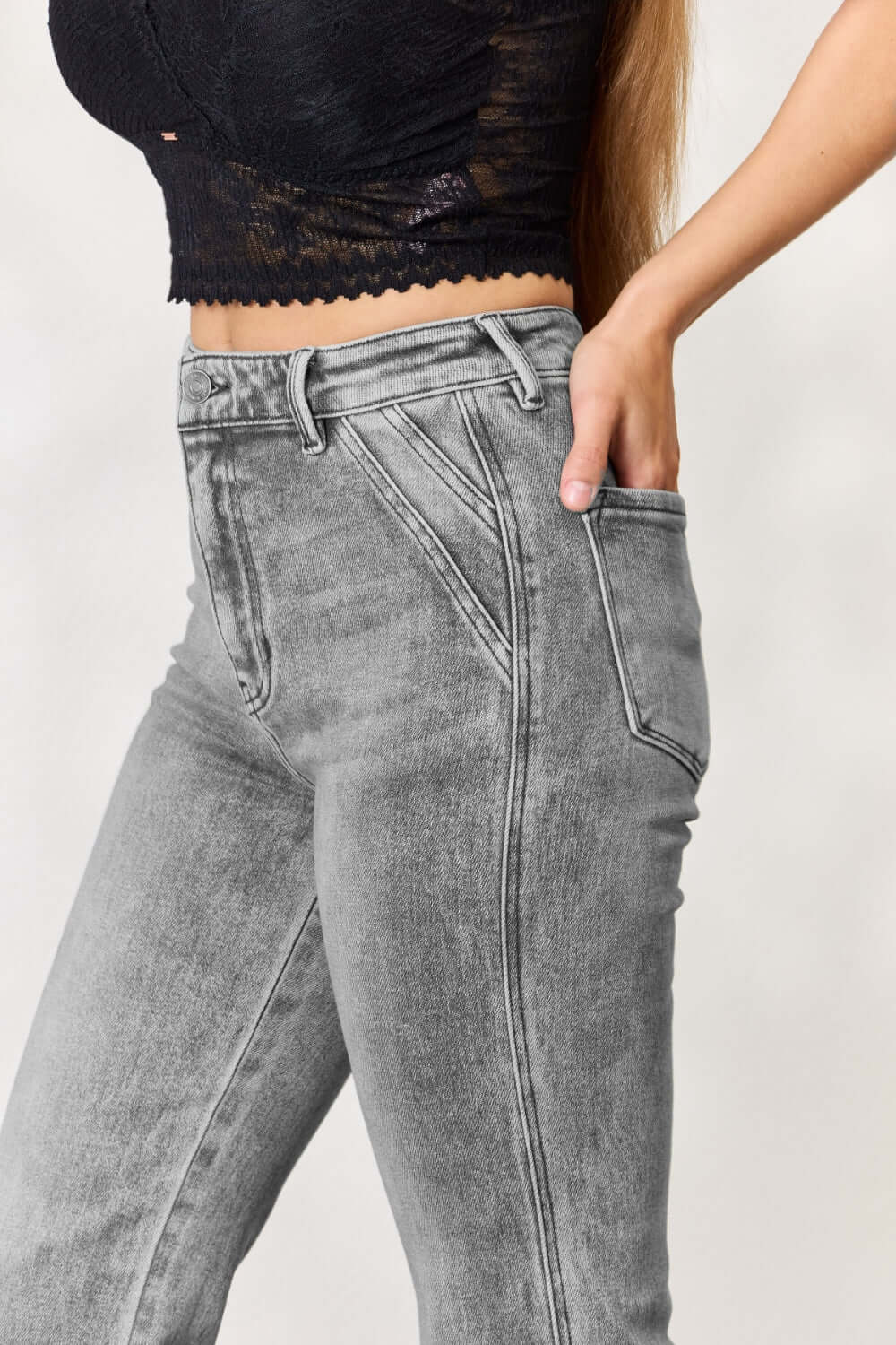 Woman wearing high waist slim flare jeans paired with a black cropped top, showcasing stylish and flattering denim fashion.