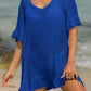 Woman wearing blue tied ruffled half sleeve cover-up with sheer fabric, standing on beach.