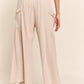 Woman wearing J.NNA smocked waist boho wide leg pants with pockets, showcasing comfortable and stylish design.