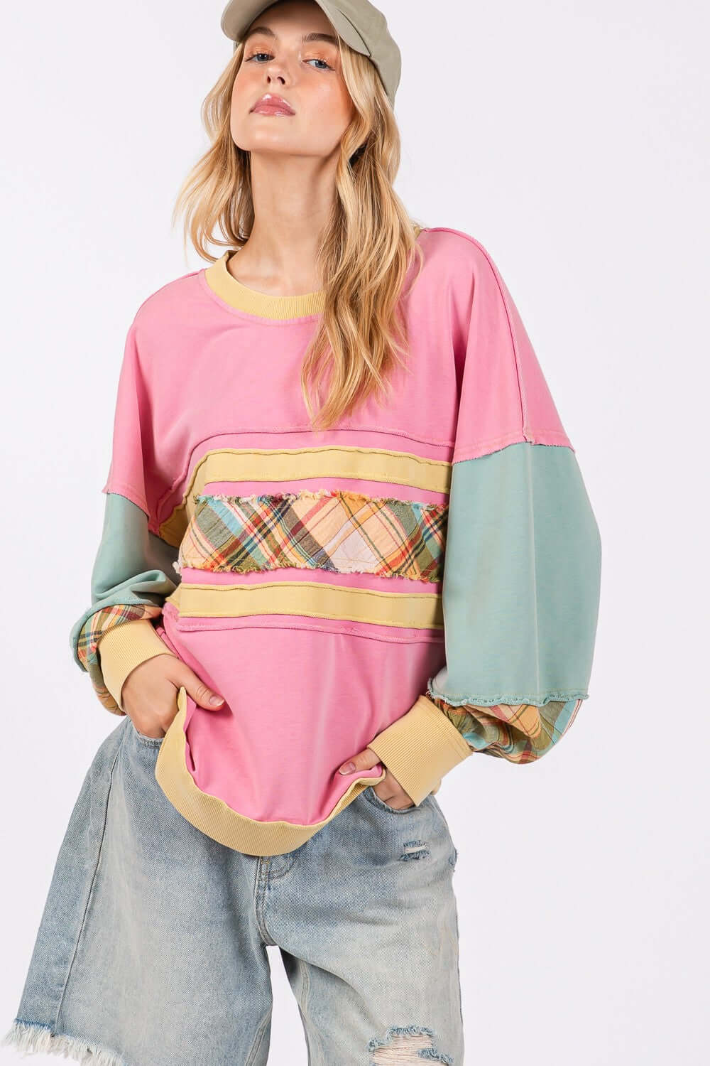 Woman wearing Mineral Wash Raw Edge Color Block Sweatshirt with plaid print front contrast and long sleeves, paired with denim shorts.