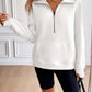 Woman wearing Ivy Lane Half Zip Raglan Sleeve Sweatshirt in white with front pocket and black shorts in a stylish indoor setting.