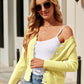 Woman wearing Bella Road Button Up Long Sleeve Cardigan in light yellow, styled with white top and jeans, accessorized with sunglasses.