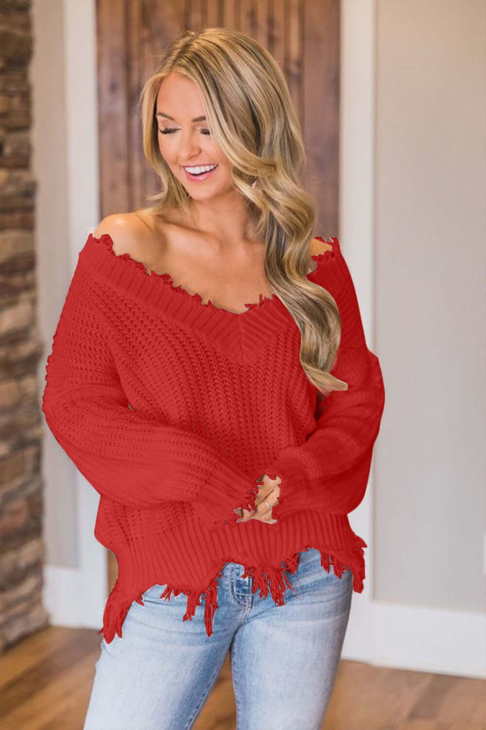 Woman wearing Bella Road frayed hem dropped shoulder sweater in red, showing off playful style with comfort.