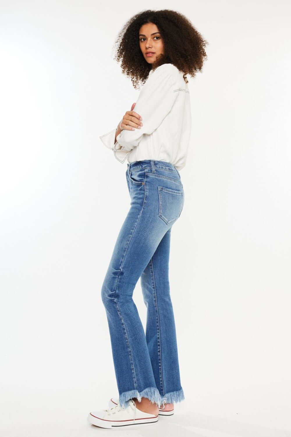 Model wearing Kancan High Rise Frayed Hem Jeans in medium stone wash, showcasing stylish and comfortable fit with raw hem detail.