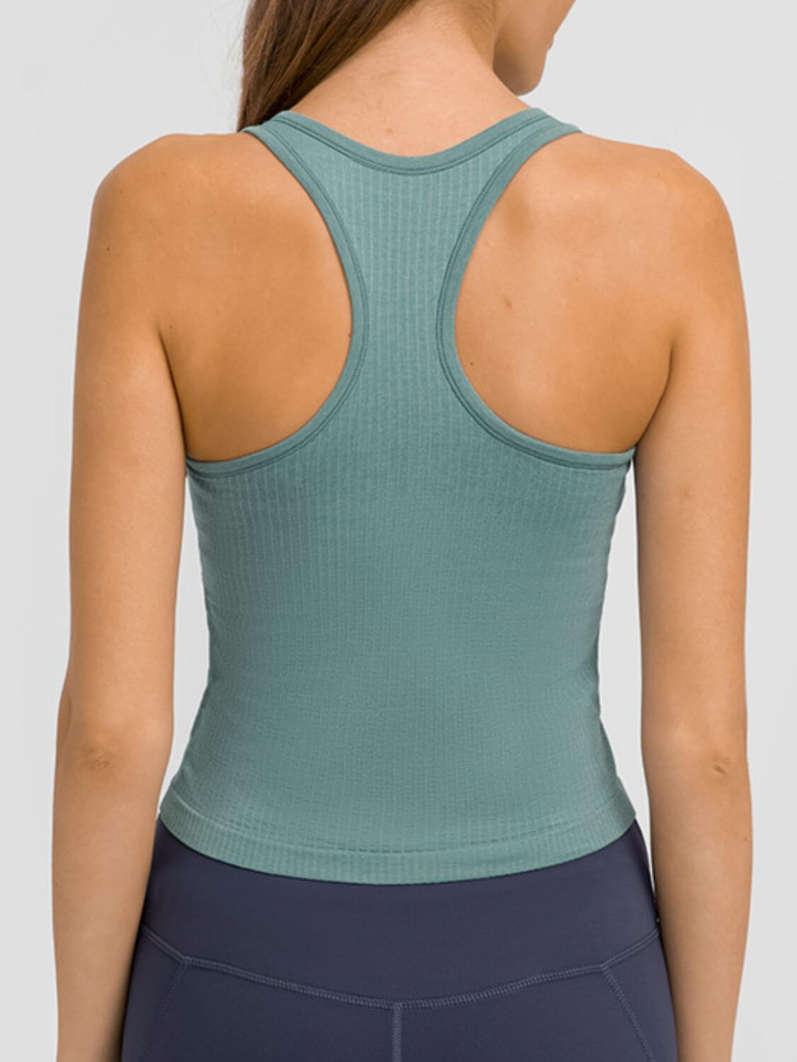 Back view of a woman wearing a Millennia Round Neck Racerback Active Tank in green for ultimate comfort and flexibility.