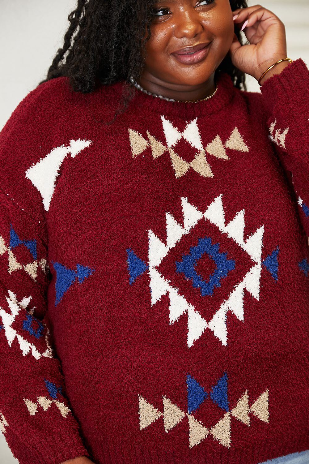 Woman wearing a HEYSON full size Aztec fuzzy sweater with vibrant red, blue, and beige pattern, showcasing cozy and artistic design.