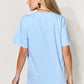 Woman wearing a light blue MAMA round neck short sleeve t-shirt, shown from the back.