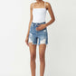 Model wearing high-waisted distressed denim shorts by Risen Jeans with a white tank top and sneakers for a casual summer look