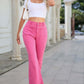 Woman wearing Bella Road Raw Hem High Waist Bootcut Jeans in pink, paired with a white crop top and white sandals.