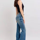 Side view of a model in Judy Blue mid rise tummy control vintage wash jeans paired with a black tank top.