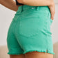 Woman wearing green high waist raw hem denim shorts from RFM Jeans.