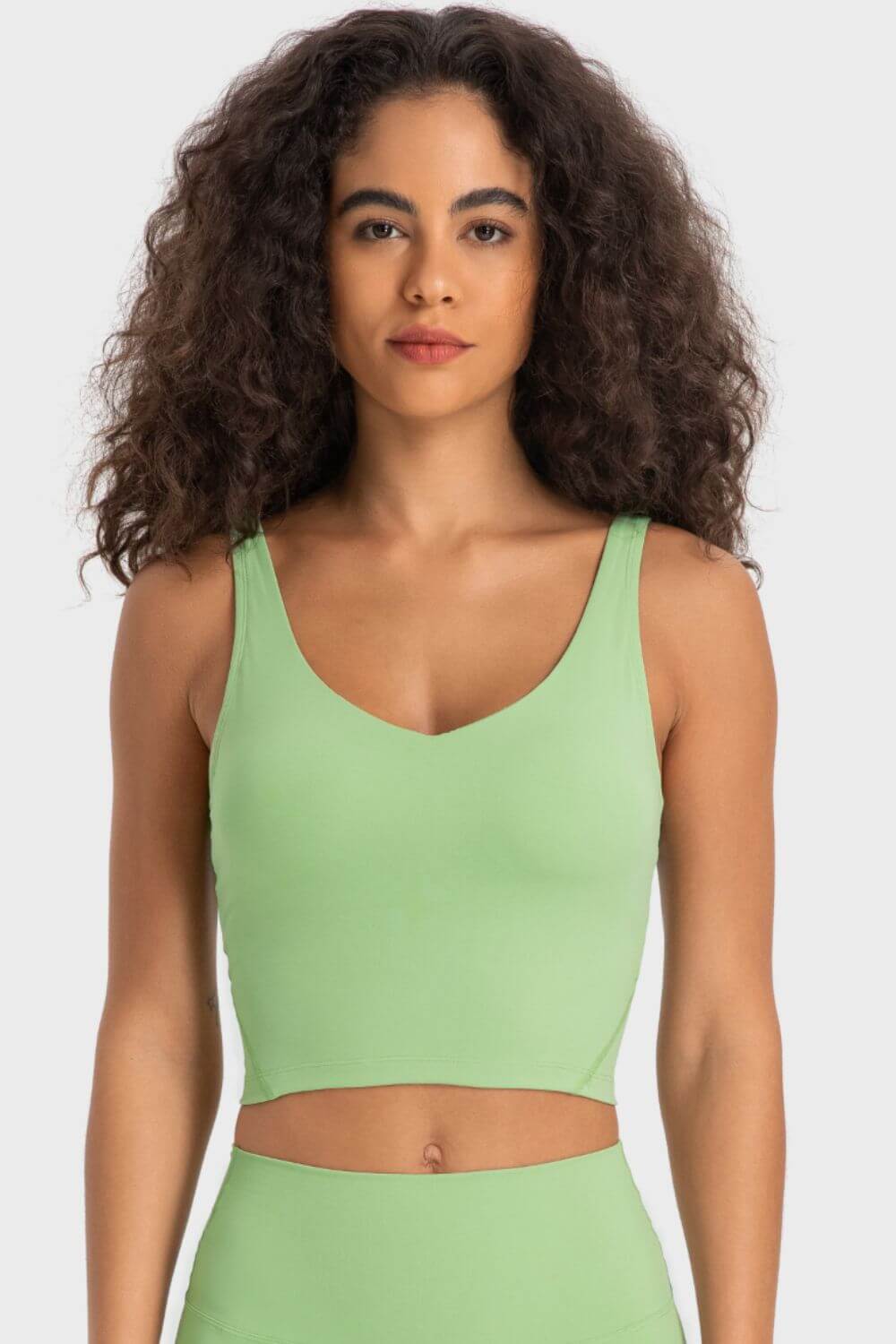 Millennia Deep V-Neck Crop Sports Bra in vibrant green, featuring a flattering fit and sleeveless design for activewear.