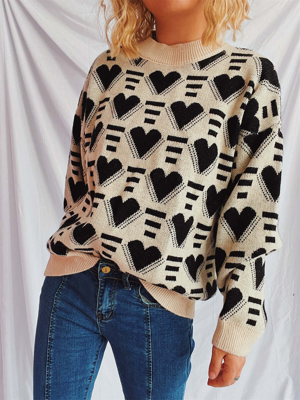 Woman wearing Bella Road Heart Contrast Long Sleeve Dropped Shoulder Sweater with heart design and jeans