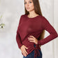 Woman wearing a burgundy drawstring round neck long sleeve top, paired with blue jeans, posing confidently against a neutral background.