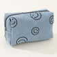 Blue corduroy cosmetic pouch with embroidered smiley faces, perfect for organizing makeup essentials in style.