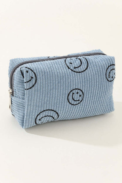 Blue corduroy cosmetic pouch with embroidered smiley faces, perfect for organizing makeup essentials in style.