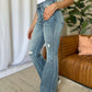 Woman wearing Judy Blue medium rise tummy control destroy flare jeans in a stylish home setting.