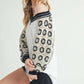 Model showcasing Aemi+Co Crochet Contrast Stitching V-Neck Top with stylish black and cream crochet sleeves.