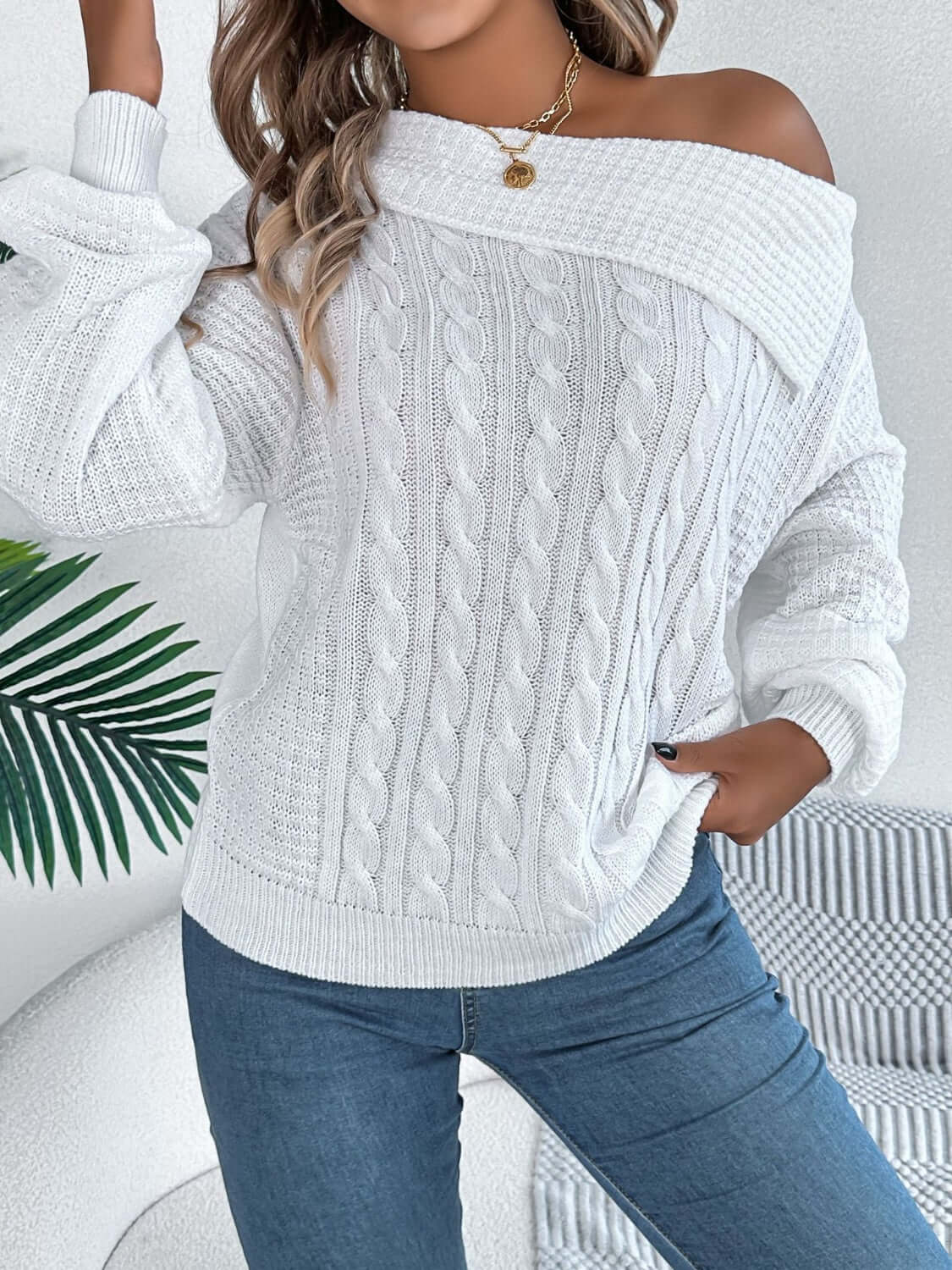 Woman wearing Bella Road cable-knit one shoulder long sleeve sweater in white, styled with jeans, showcasing casual yet stylish outfit.