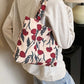 Person wearing a medium-sized printed canvas handbag with zipper, featuring red floral design. Perfect for a casual day out.