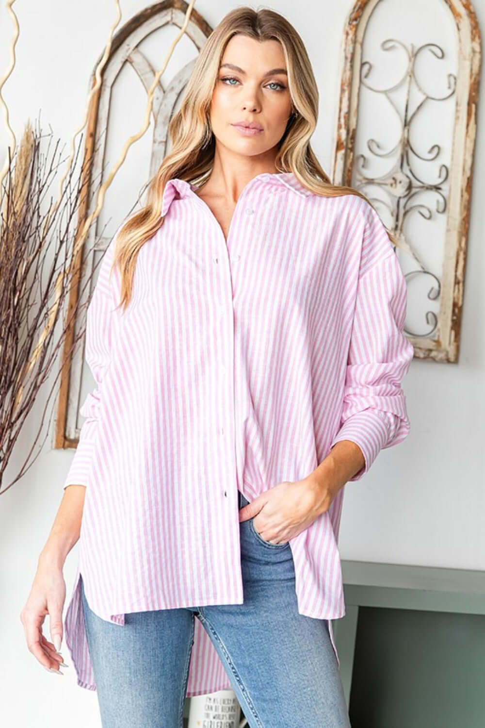 Woman wearing a First Love Full Size Striped Button Down High-Low Hem Shirt in pink and white stripes with blue jeans.