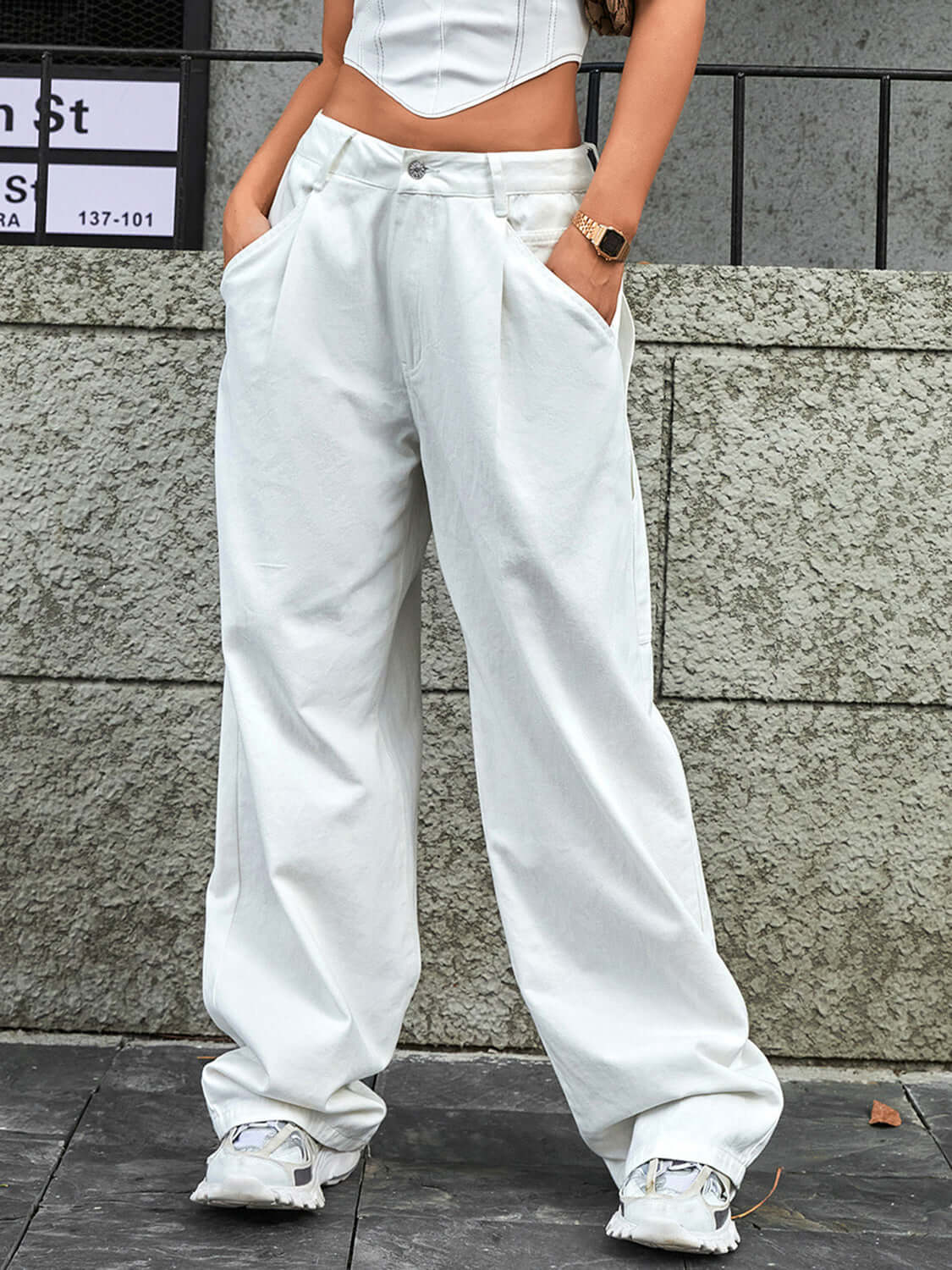 Woman wearing Bella Road wide leg jeans with pockets and a low waist, styled with a top and sneakers against an urban background.