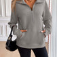 Woman wearing Ivy Lane Half Zip Raglan Sleeve Sweatshirt with pockets and black shorts, holding a black handbag.