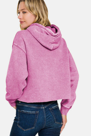 Woman wearing a pink Zenana Acid Wash Fleece Cropped Hoodie, showcasing a trendy and vintage-inspired style.