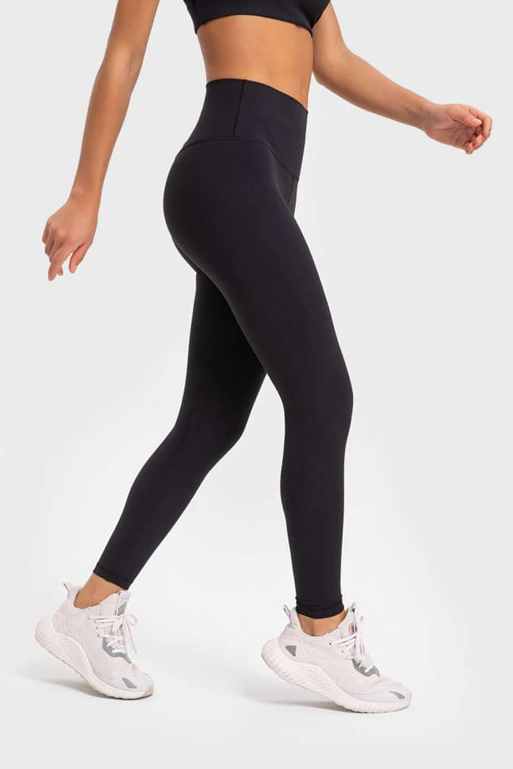 Woman in black Millennia Highly Stretchy Yoga Leggings with wide waistband, showcasing comfort and style for workouts.