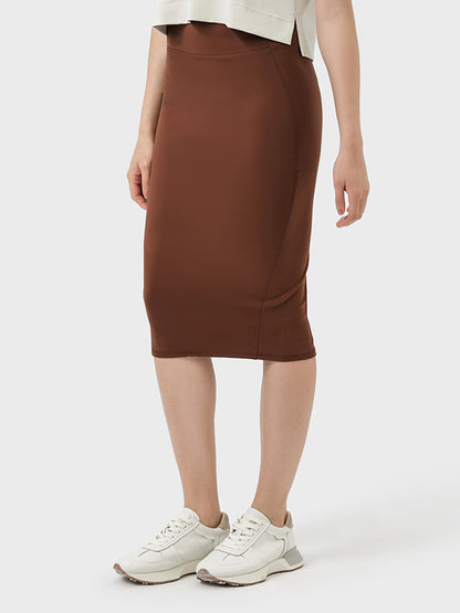 Model wearing a Millennia Slit Wrap Active Skirt in brown, paired with casual shoes and a stylish top.