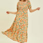 Woman twirling in floral smocked tiered midi dress, showcasing the elegant summer style and vibrant print of HEYSON dress.