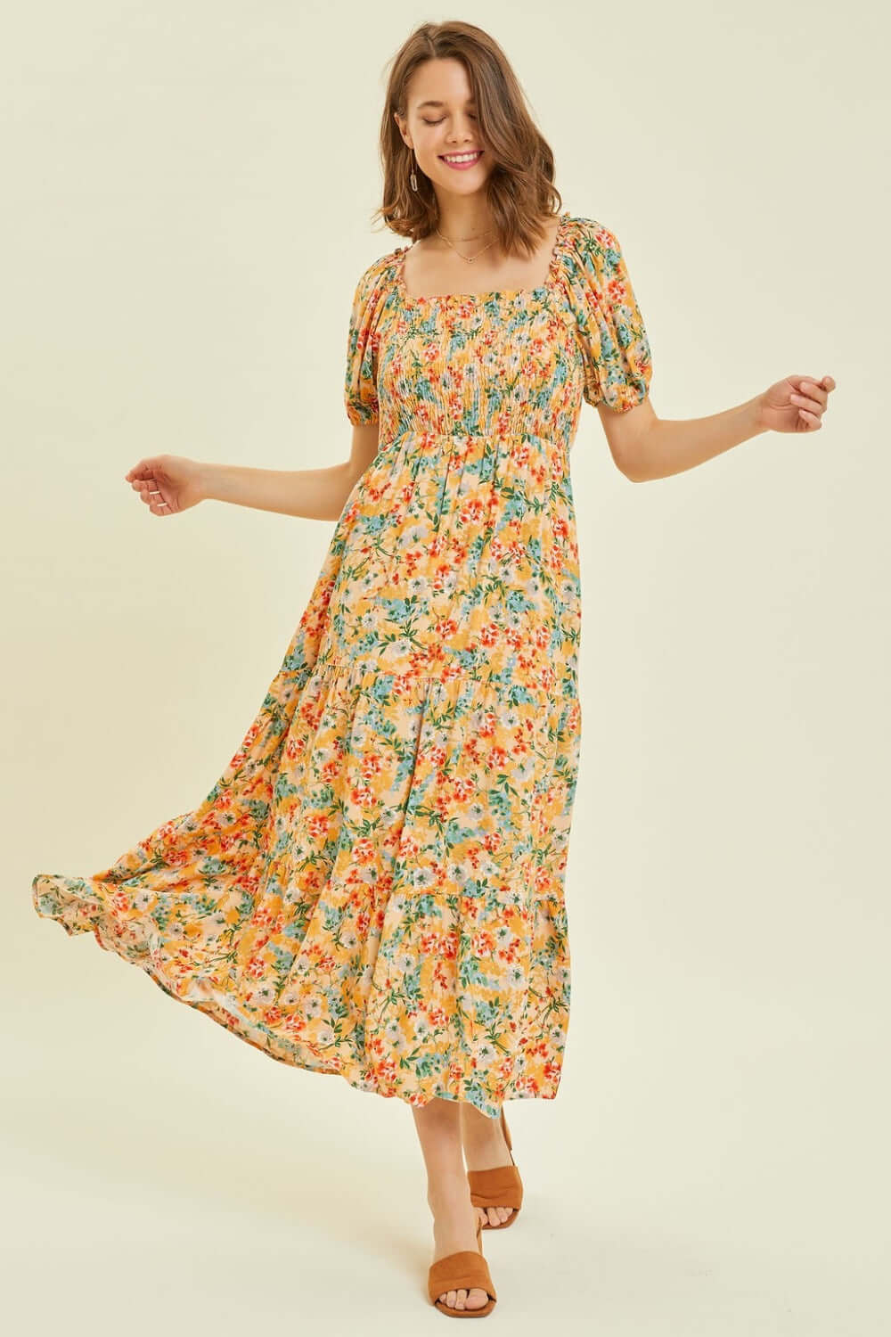 Woman twirling in floral smocked tiered midi dress, showcasing the elegant summer style and vibrant print of HEYSON dress.