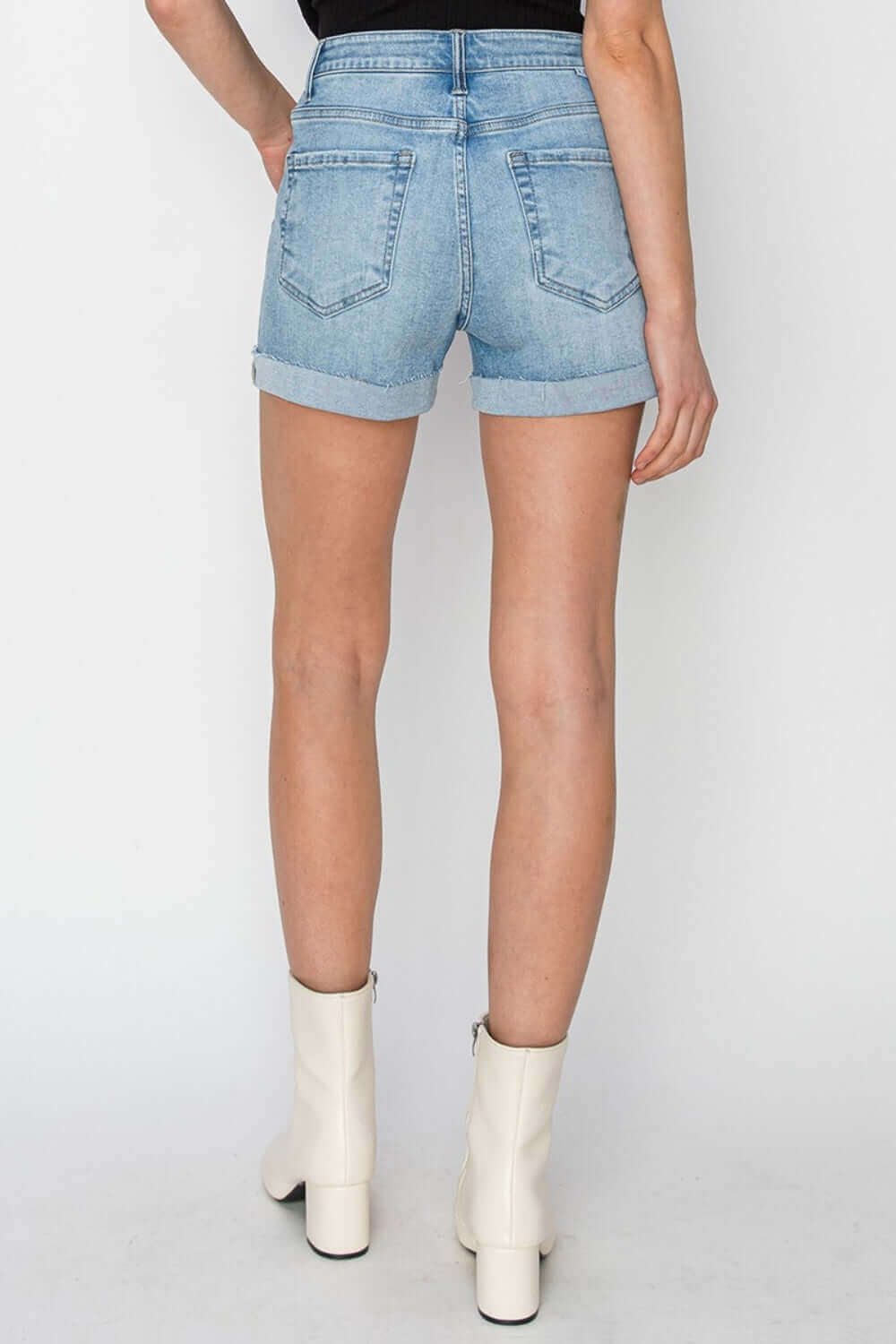 Back view of Distressed Mid-Rise Waist Denim Shorts by Risen Jeans, showcasing trendy distressed detailing and stylish summer fashion.