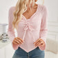 Woman wearing Bella Road Ribbed Drawstring Long Sleeve T-Shirt in light pink with casual jeans in a cozy room.