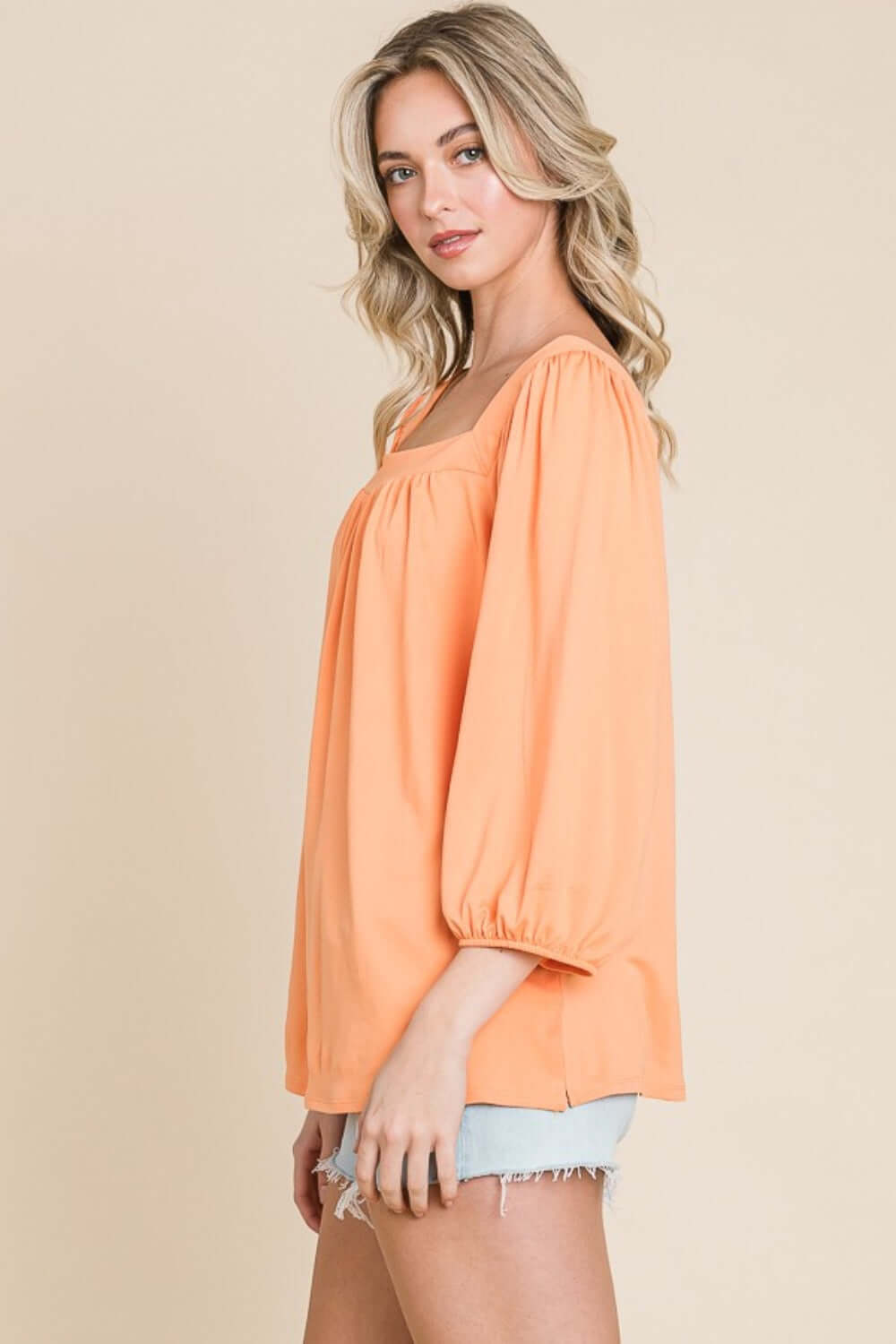 Woman wearing a trendy Square Neck Puff Sleeve Top with chic and modern design, styled with light denim shorts.