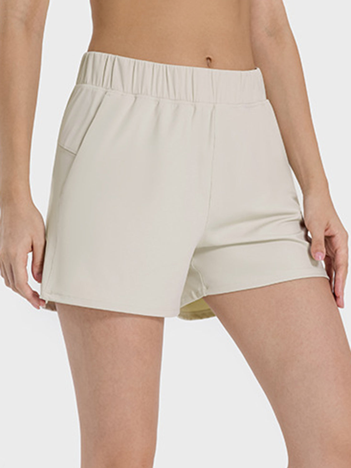 Millennia Elastic Waist Active Shorts in light beige, showcasing a comfortable fit and handy side pockets. Perfect for active wear!