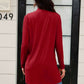 Woman wearing red open front long sleeve cardigan with pockets, standing in front of a black door, showcasing back design.